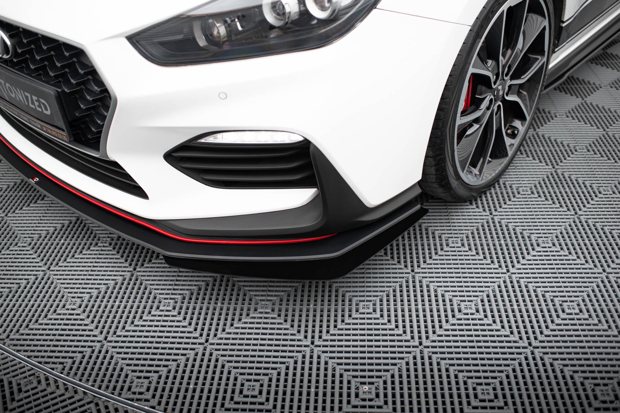 Front splitter på Hyundai I30 N MK3 med svart spoiler, rød stripe og sorte felger med røde bremsekalipere.