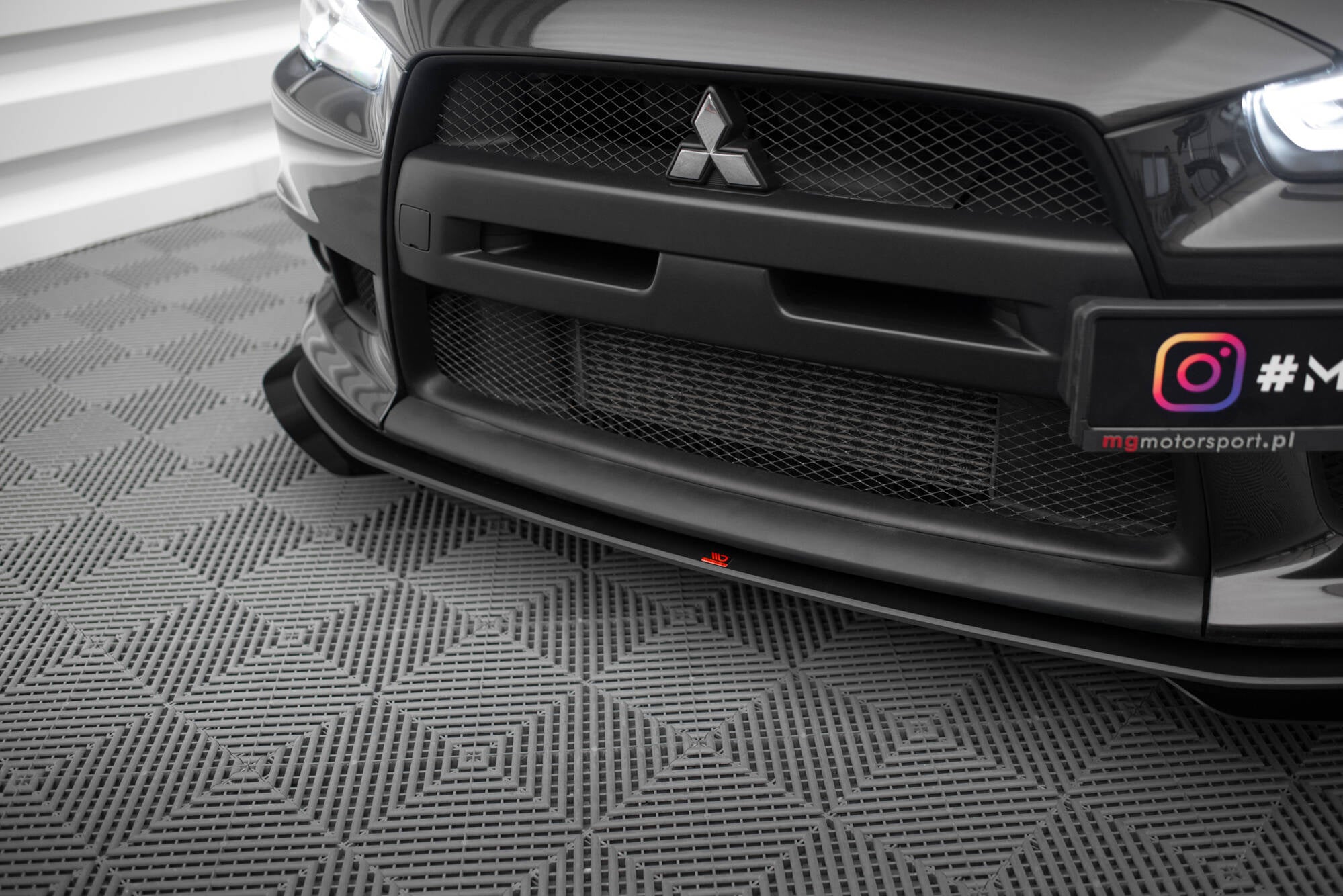 Frontleppe til Mitsubishi Lancer Evo X med riller og rød detalj, nærbilde montert forfra på bil.