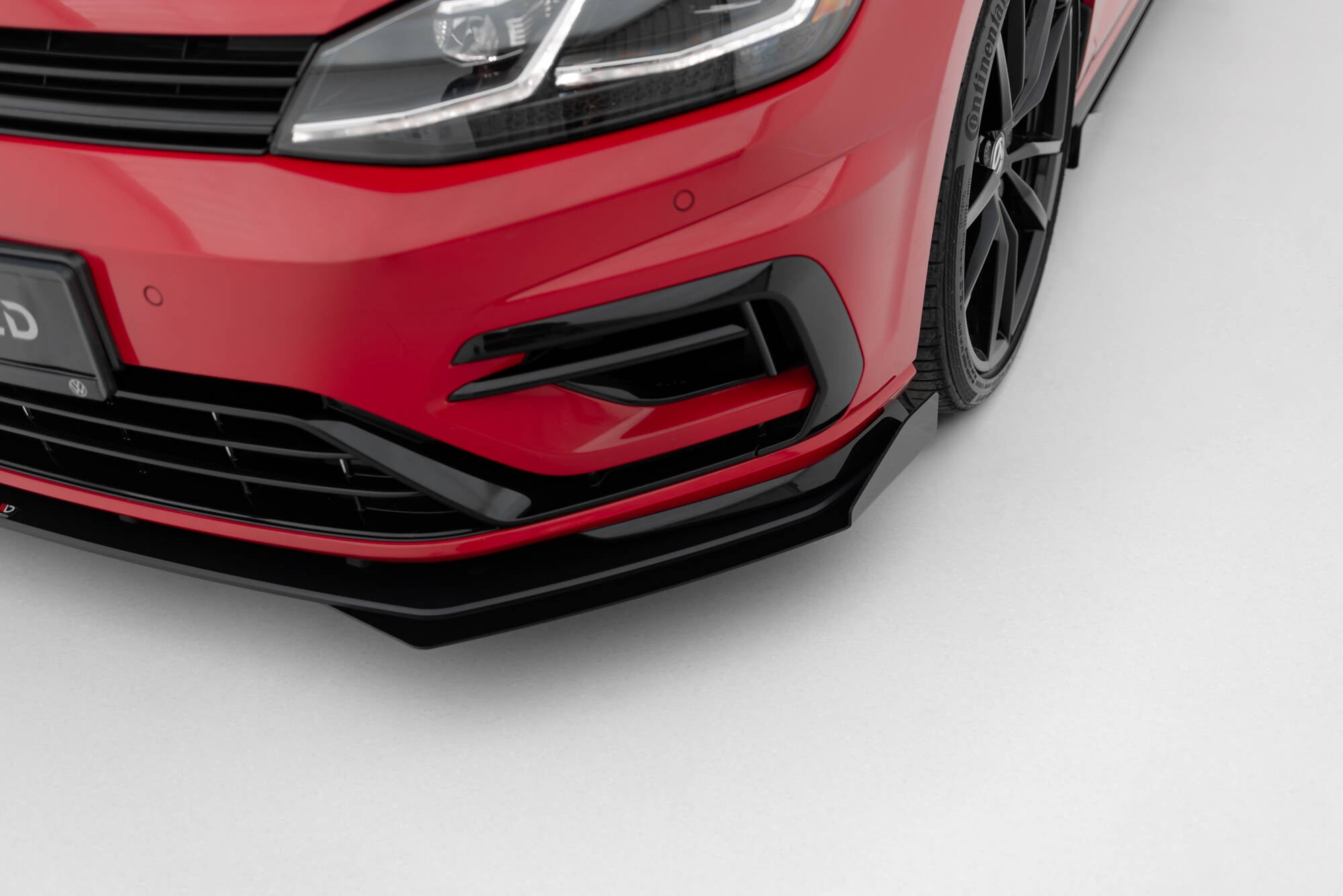 Front splitter på VW Golf R MK7 facelift, blank svart plast, lav vinkel mot høyre hjørne, sorte felger.