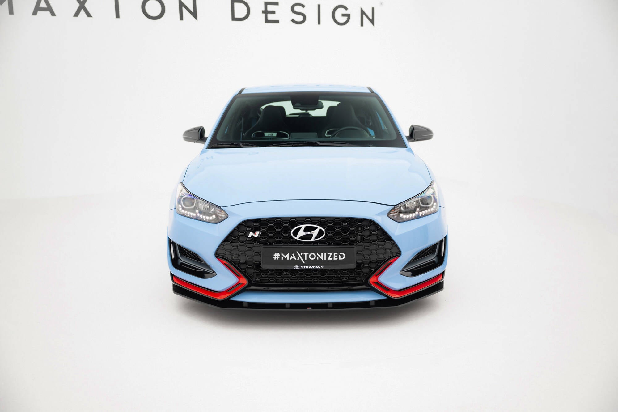 Frontleppe Hyundai Veloster N MK2 V1 montert på lyseblå sportsbil med sorte og røde detaljer, studiobakgrunn.