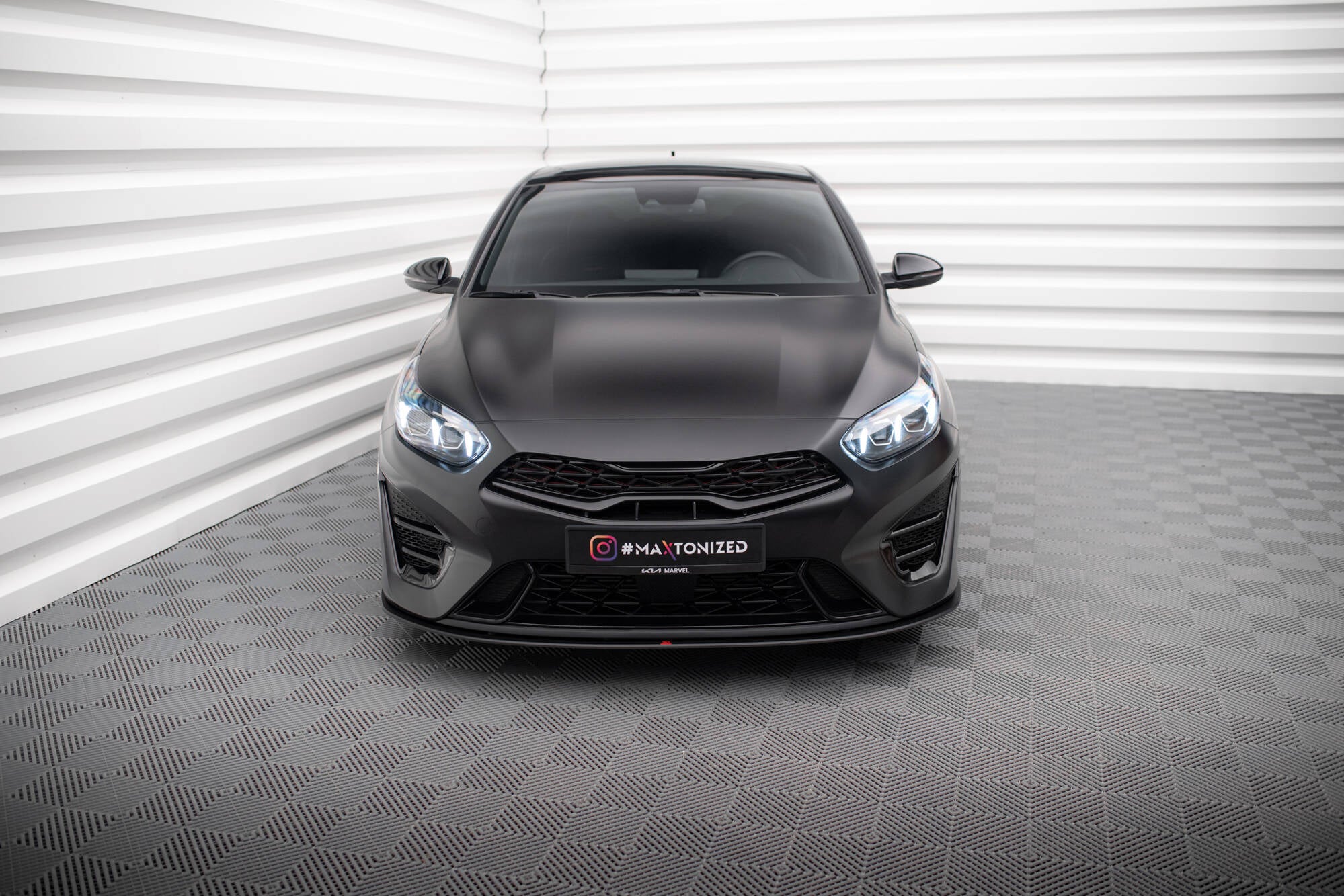 Frontleppe på matt svart Kia Proceed GT MK3 Facelift med LED-lys, sett forfra i lyst rom.