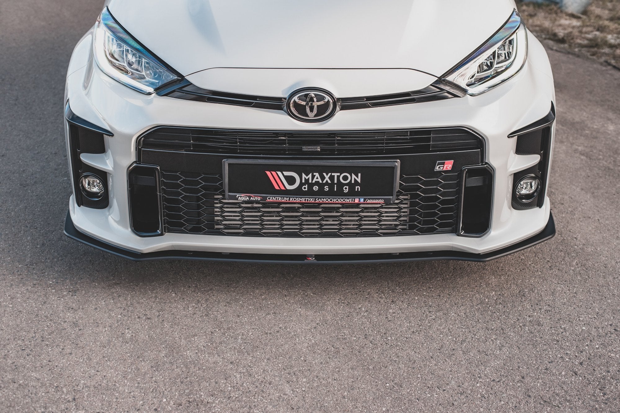 Frontspoiler Toyota Gr Yaris MK4 med sort grill, Maxton Design-logo og sporty linjer, sett rett forfra.