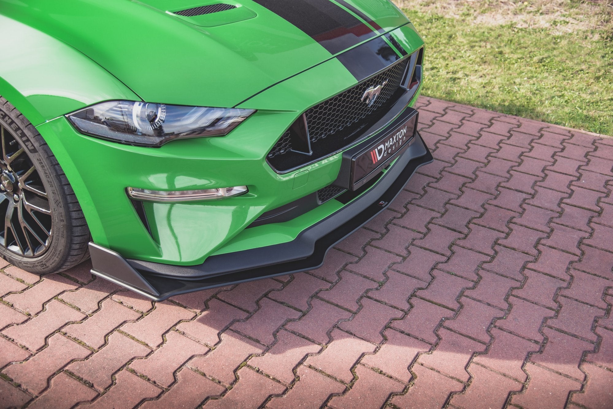 Frontspoiler til Ford Mustang GT MK6 Facelift V.2 på grønn bil med svart stripe, sett fra skrå vinkel.