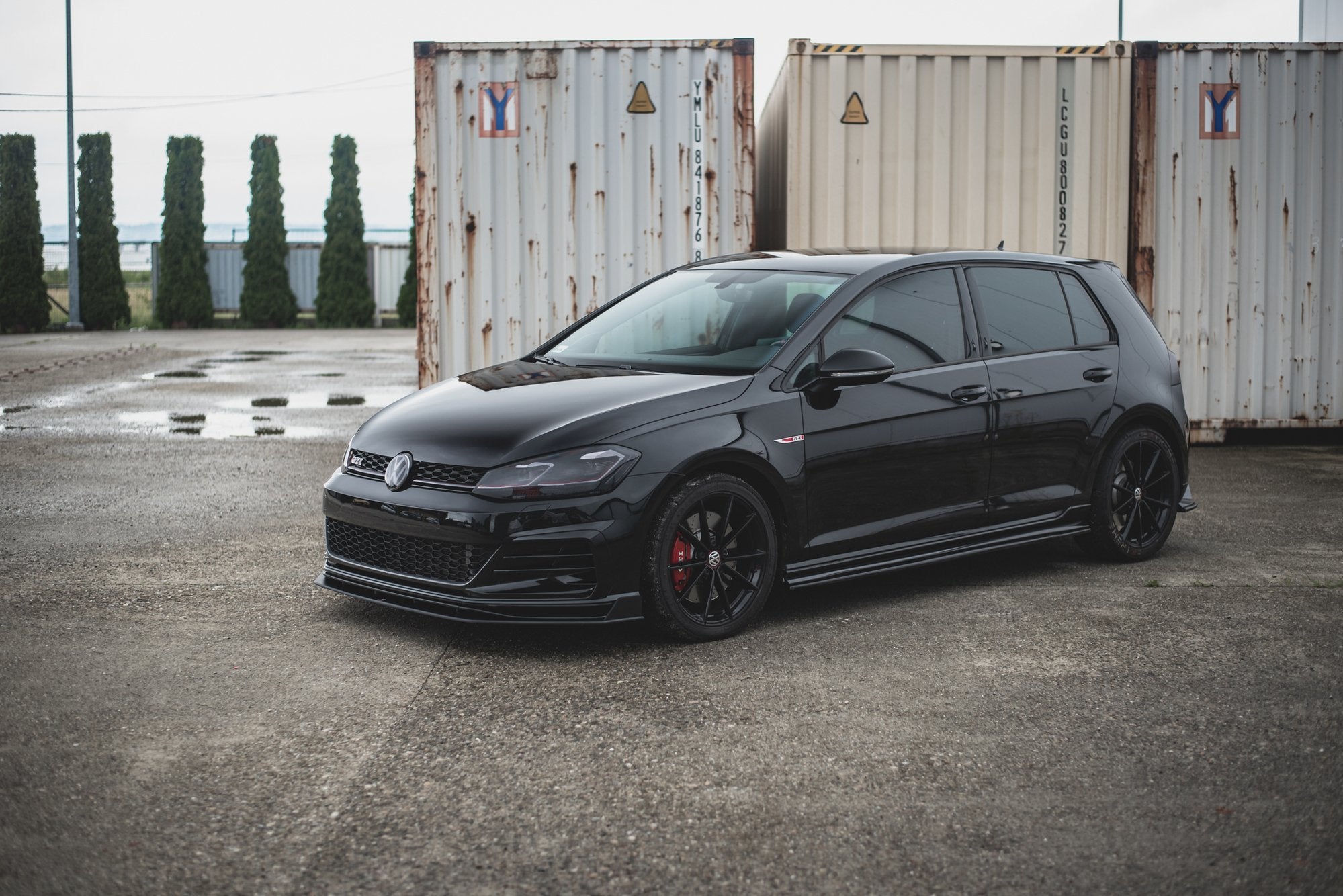 Front lip på VW Golf 7 GTI Tcr med svarte felger og røde bremsekalipere utendørs.