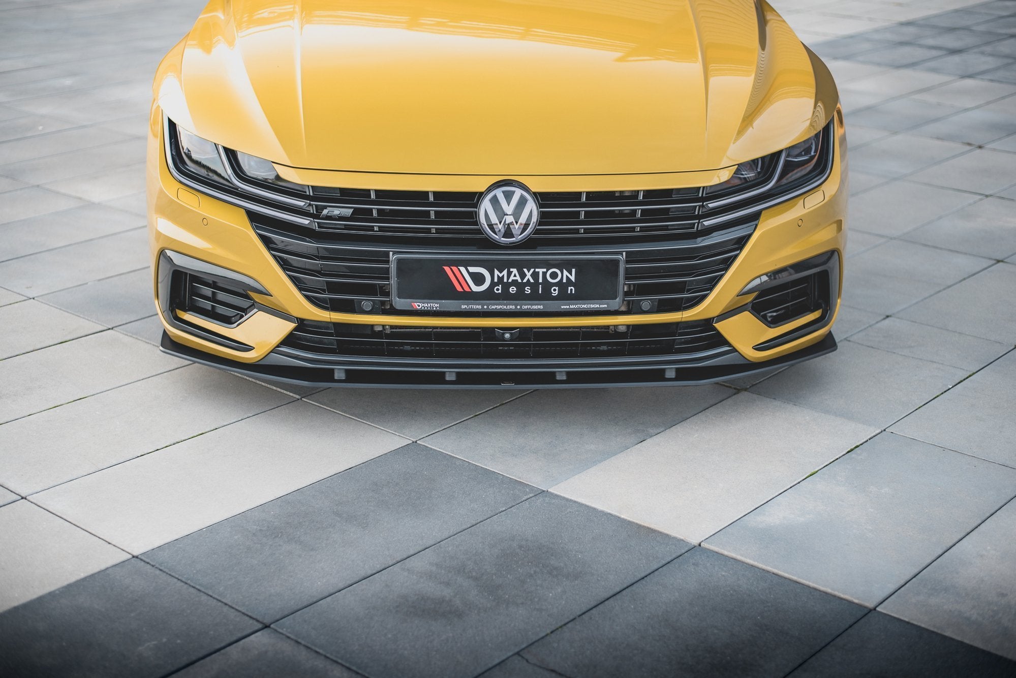 Frontspoiler VW Arteon R-Line på gul bil med sorte detaljer og store luftinntak, sett rett forfra.