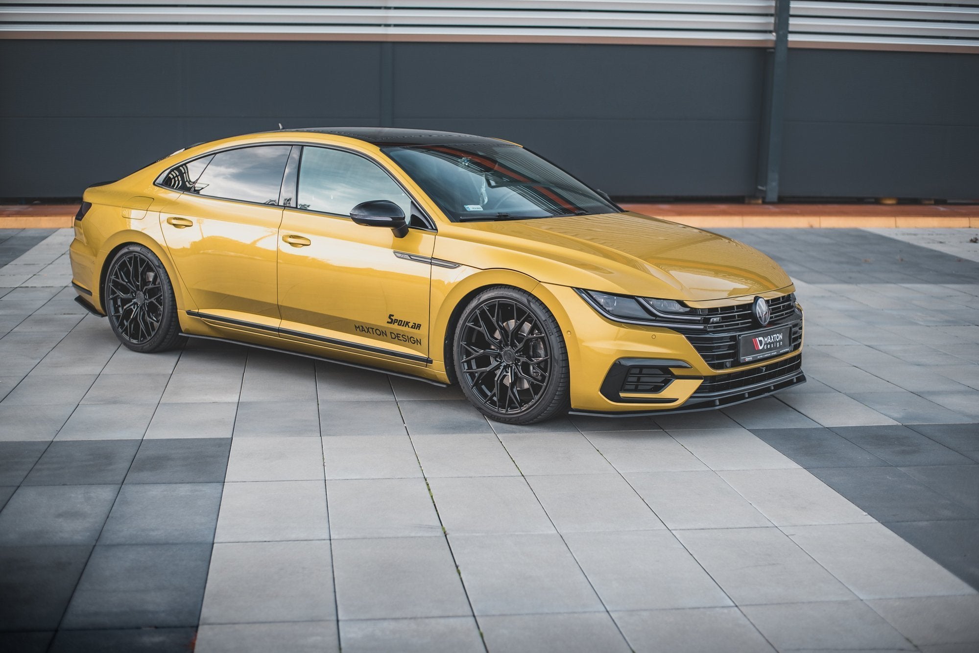 Front splitter på VW Arteon R-Line i metallic gul med sorte felger, dekaler og panoramatak sett fra siden.