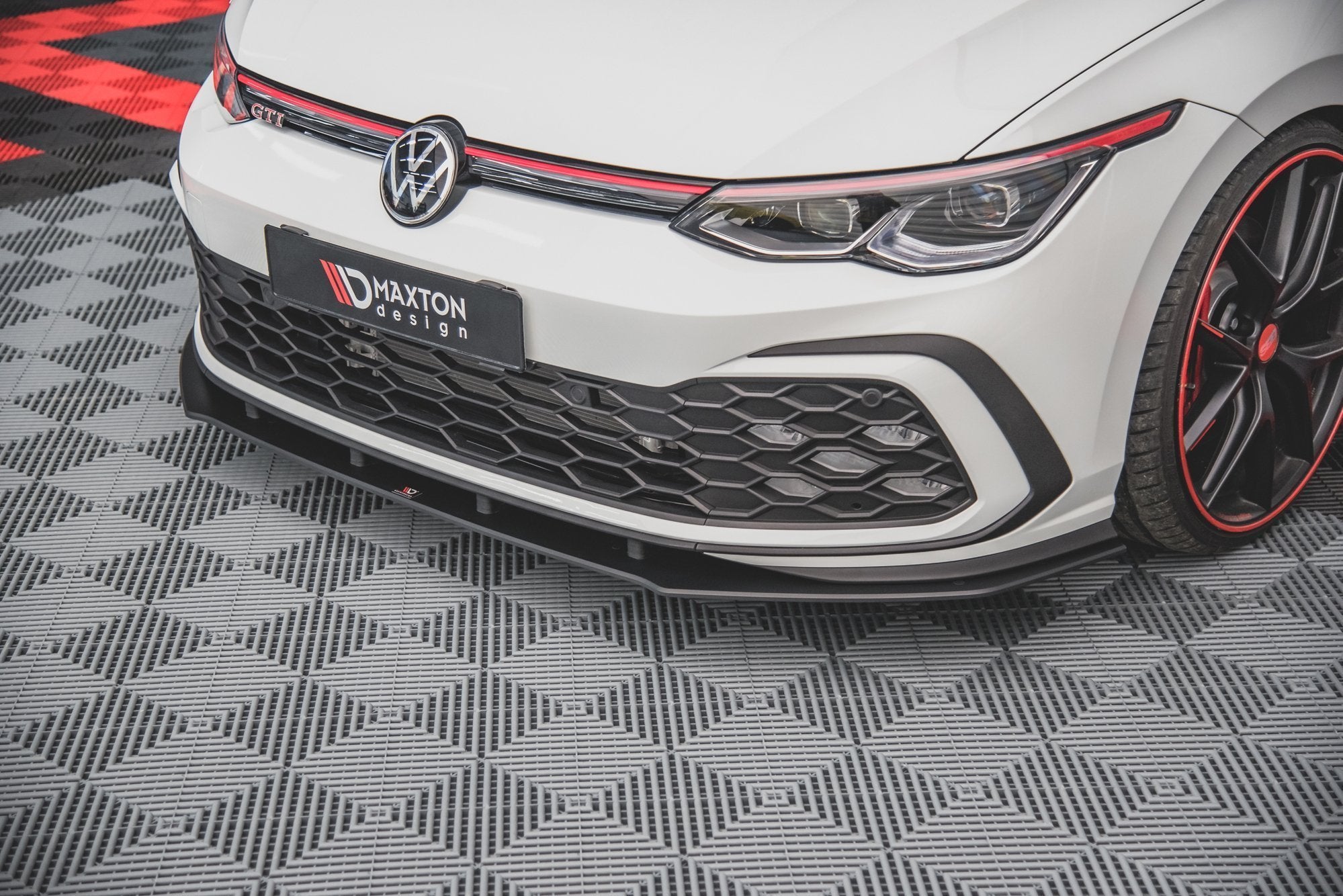 Frontleppe til VW Golf MK8 montert på hvit bil med sort grill og røde detaljer på felgene.