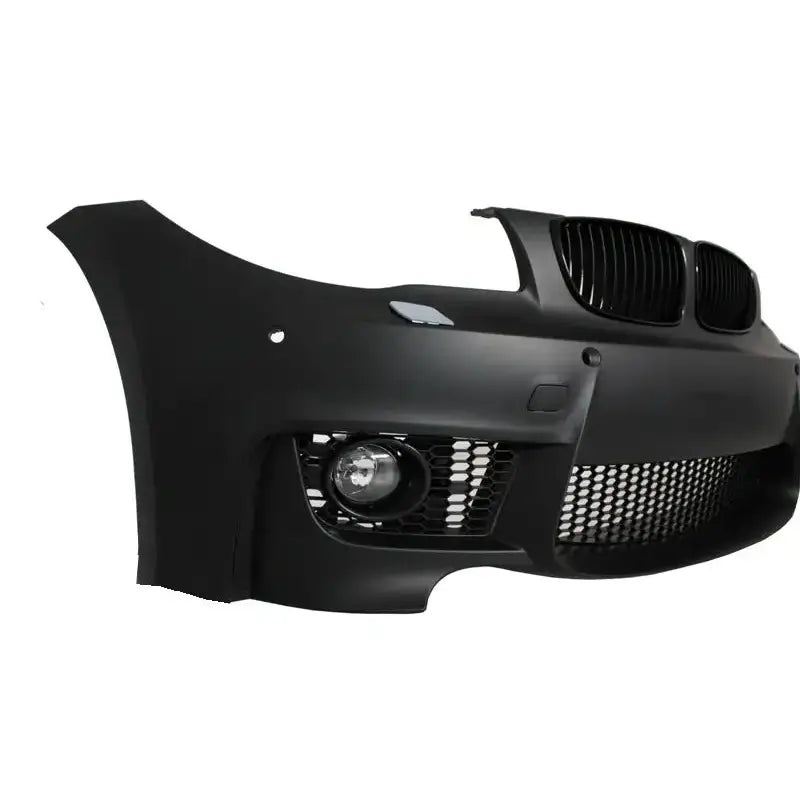 Frontfanger til BMW 1 Serie E88 07-11 i sort plast med grill og tåkelykt, skrå forfra mot hvit bakgrunn.