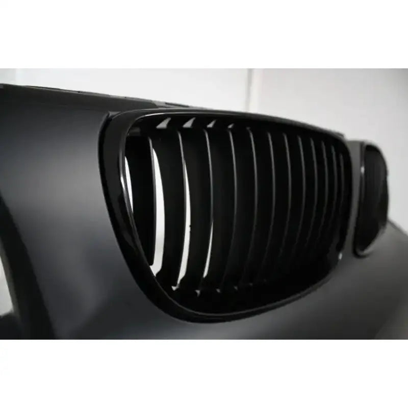 Frontbumper til BMW 1 Serie E88 07-11 med sort blank plast og vertikale lameller sett fra skrå vinkel.
