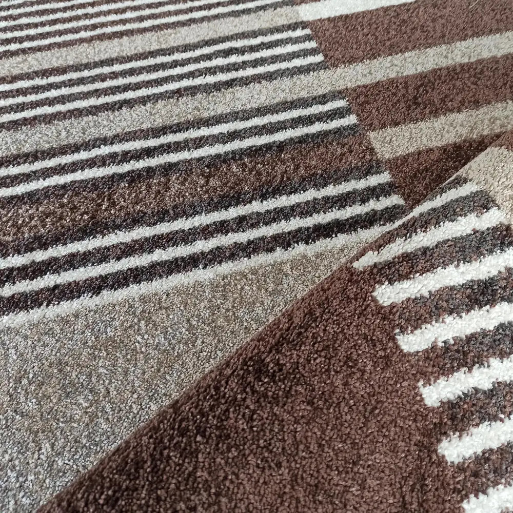 Tepe Otto teppe i brun, beige og hvit, nærbilde av stripete mønster og myk lugg med brettet kant.