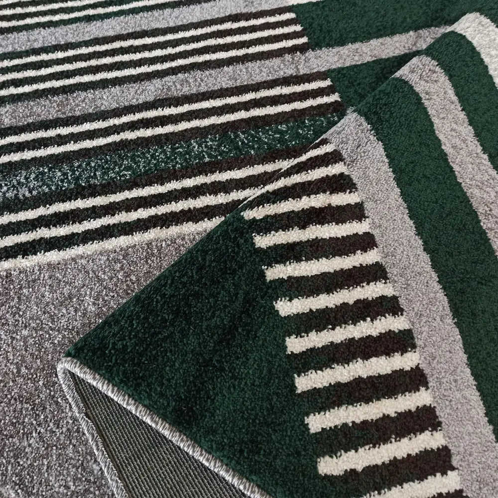 Tepe Otto teppe i grått og grønt, nærbilde av stripemønster og oppbrettet hjørne som viser tekstur.