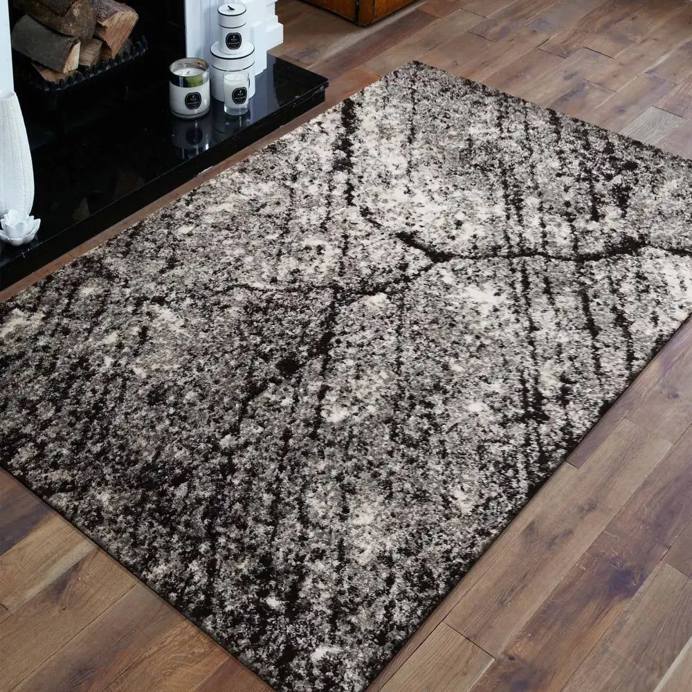Tepe Panamero teppe 200 x 290 cm, grå og svart abstrakt mønster, sett ovenfra på lyst tregulv.
